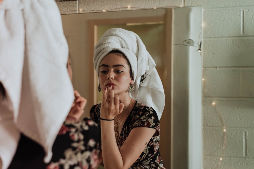 woman in front of mirror doing make up