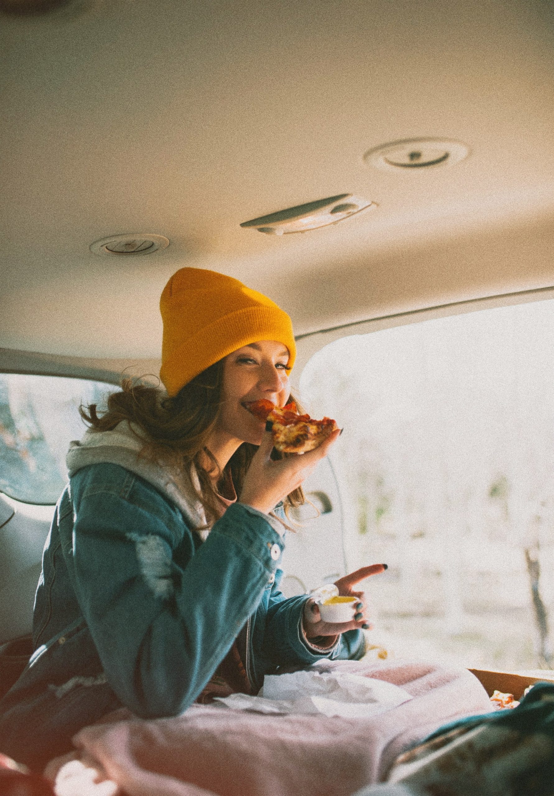 woman eating pizza in a car